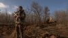 FILE - A Ukrainian serviceman stands guard checking for Russian drones in the sky as a soldier in a tractor digs a trench system in the Zaporizhzhia region, on January 30, 2024, amid the Russian invasion of Ukraine.