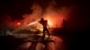 A firefighter sprays the smoldering remains of a vehicle on Interstate 5 as the Delta Fire burns in the Shasta-Trinity National Forest, Calif., on Sept. 5, 2018. 