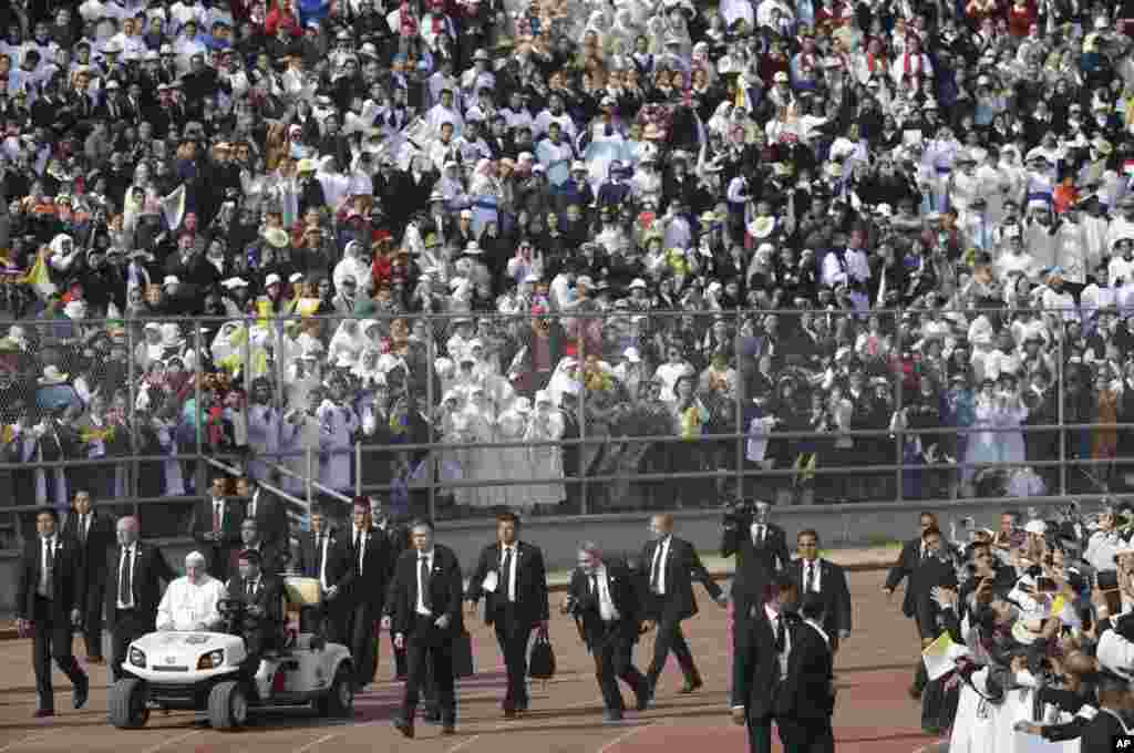Pope Francis, followed by security guards, arrives in a golf cart to celebrate Mass at the Venustiano Carranza stadium in Morelia, Mexico.