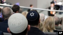 FILE - Two men wearing skullcaps as they listen to the speech of Israeli Historian Saul Friedlaender, during a remembrance event of the parliament Bundestag to commemorate the victims of the Holocaust at the Reichstag building in Berlin, Germany, Jan. 31, 2019.