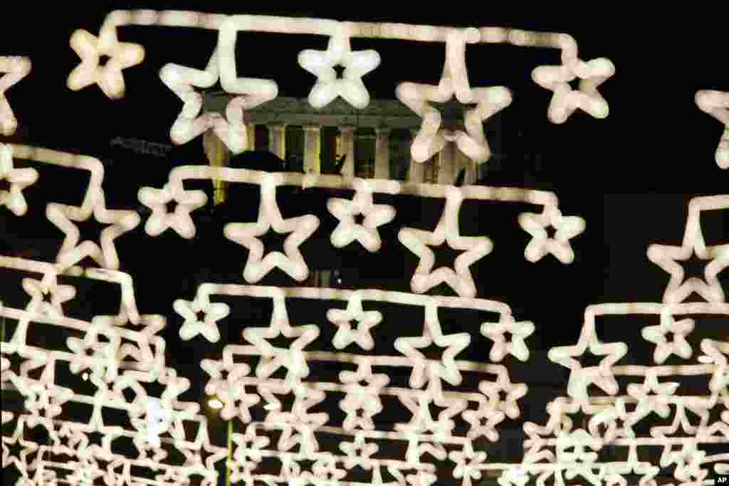 The ancient Parthenon temple on the Acropolis appears behind strings of Christmas lights in central Athens, Greece.