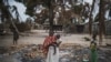 FILE - A woman holds her child while standing in a burned out area in the attacked village of Aldeia da Paz outside Macomia in Cabo Delgado Province, in Mozambique, Aug. 24, 2019.