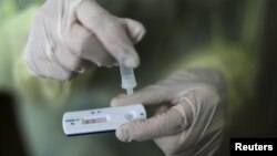 FILE - A health care worker holds a rapid COVID-19 antigen test at a coronavirus testing center in Nice, France, Oct. 15, 2020. Millions of such kits are heading to Africa for distribution.