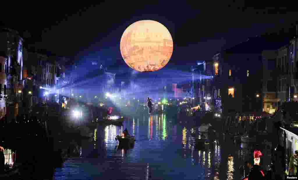 A masked reveler hangs from an inflatable balloon during the first day of the carnival in Venice, Italy, Jan. 23, 2016.