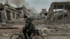 FILE - A man rides on a bike in front of the mail office which was destroyed by a Russian airstrike in Kurakhove, Donetsk region, Ukraine, on Nov. 7, 2024.