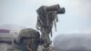 A service member of the Ukrainian armed forces uses binoculars while observing the area at fighting positions on the line of separation near the rebel-controlled city of Donetsk, Ukraine, April 6, 2021.