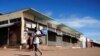 FILE - A man wears a mask as he walks past closed shops during a lockdown aimed at limiting the spread of the coronavirus disease (COVID-19) in Harare, Zimbabwe, Jan. 28, 2021.