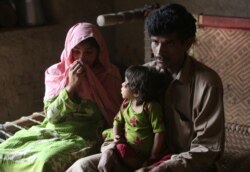 FILE - Pakistan's Tariq Ali, 30 along with his wife Parveen and three-year-old Ume Kulssom all infected with HIV sit at their home in a village near Ratodero, May,16, 2019.