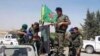 FILE - In this file photo released June 23, 2015, provided by the Kurdish fighters of the People's Protection Units (YPG), Kurdish fighters of the YPG sit on their pickup in the town of Ein Eissa, north of Raqqa city, Syria.