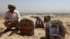 FILE - An Afghan man prays in front graves of victims of a suicide attack, in Kabul, Afghanistan, July 25, 2016. 
