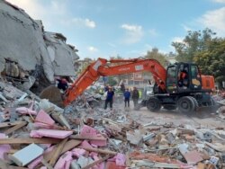 People search for survivors at a collapsed building after a strong earthquake struck the Aegean Sea where some buildings collapsed in the coastal province of Izmir, Turkey, Oct. 30, 2020.