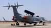 Engineers and support staff sit in the shade of an Embraer EMB-145I aircraft fitted with the India's first indigenous airborne radar system during rehearsals for the Aero India 2015 at Yelahanka air base in Bangalore, India, Feb. 17, 2015.
