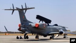 Engineers and support staff sit in the shade of an Embraer EMB-145I aircraft fitted with the India's first indigenous airborne radar system during rehearsals for the Aero India 2015 at Yelahanka air base in Bangalore, India, Feb. 17, 2015.