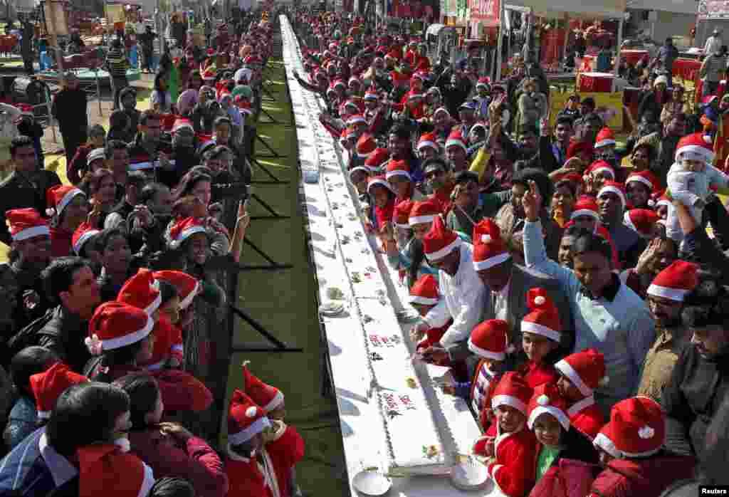 People pose next to a 76-meter (251-foot-long) cake during Christmas celebrations at a consumer fair in Chandigarh, India.