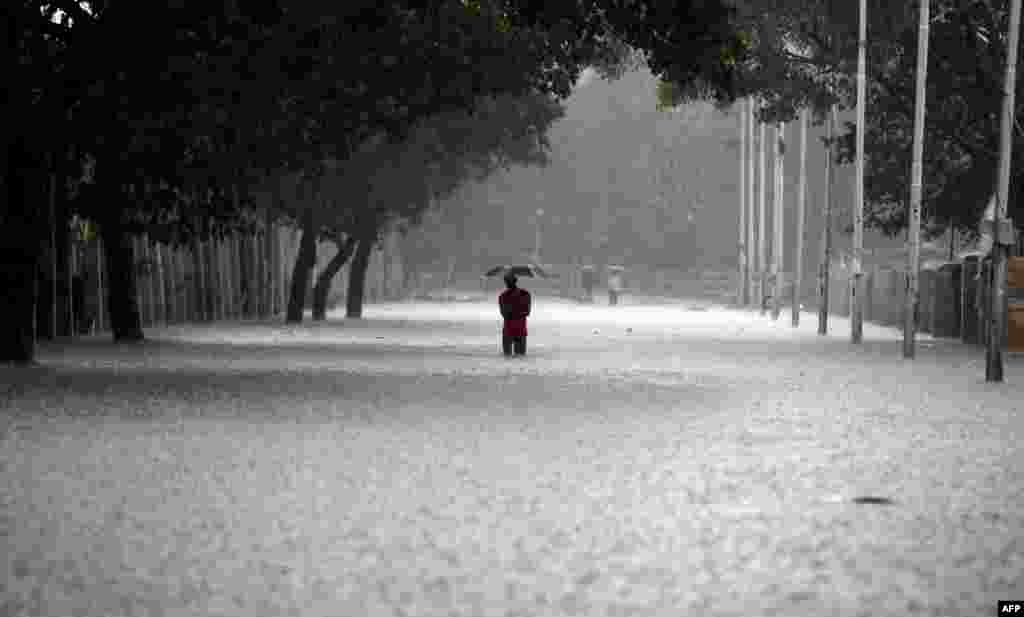 An Indian man shelters under an umbrella as he walks through floodwaters in Chennai in heavy rain.