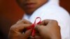 FILE - A red ribbon is put on the sleeves of a man by his friend to show support for people living with HIV during a program to raise awareness about AIDS on World AIDS Day in Kathmandu, Dec. 1, 2013. 