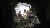 FILE - Boys look through a hole made by a Saudi-led airstrike on a bridge in Sanaa, Yemen, March 23, 2016. 