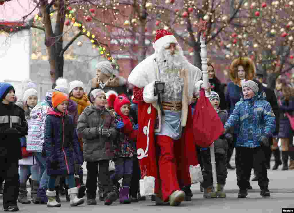 An actor dressed as Ded Moroz, the Russian equivalent of Santa Claus, accompanied by children, walks in Red Square in central Moscow.